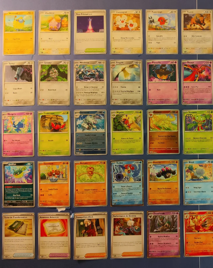 Trente cartes Pokémon toutes différentes, extraites d'une tranche de 50 et posées en grille sur un tapis bleu : Métalosse, Keldeo, Feunard et Pitrouille, entre autres.